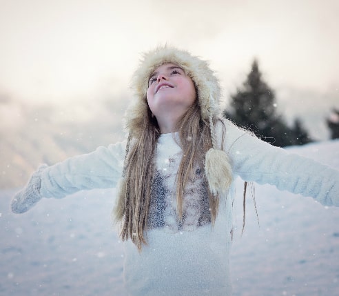 A young girl in winter clothing playing in the snow