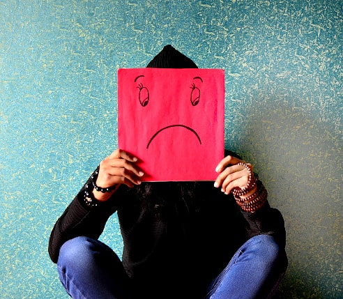 A man holding a picture of a sad face