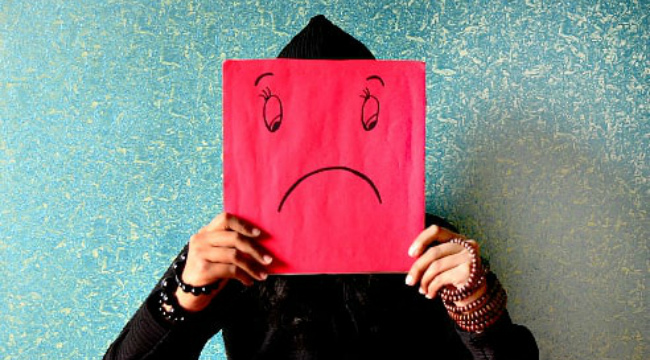 A man holding a picture of a sad face