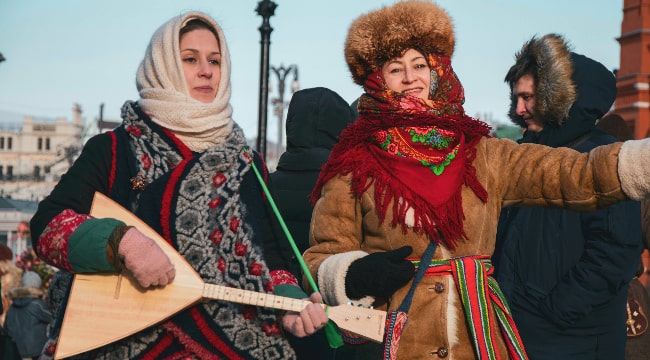 Russian women in traitional costumes invite to celebrating Maslenitsa